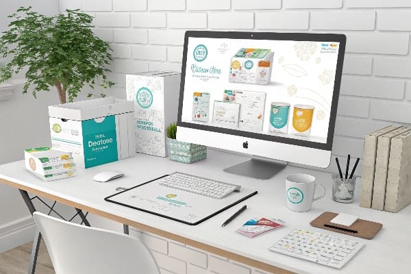 Configuração moderna do espaço de trabalho com designs de embalagens de produtos para bebês exibidos na tela e mesa