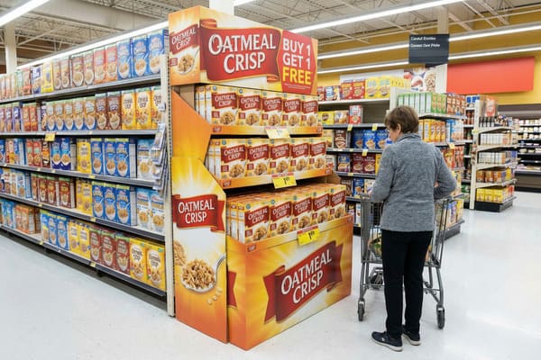 A woman with a shopping cart stands in a brightly lit grocery store aisle, examining cereal boxes. A large promotional display for 'Oatmeal Crisp' cereal, featuring a 'Buy 1 Get 1 Free' offer, is prominently displayed. Various other cereal brands are visible on shelves in the background.
