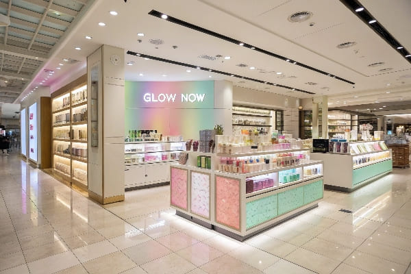 Schönheitsanzeige im Kaufhaus mit Pastellfarben und 'Glow Now' Signage