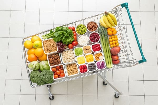 カラフルな果物、野菜、パッケージ化された食品がきちんと配置された食品で満たされたショッピングカートのトップダウンビュー。