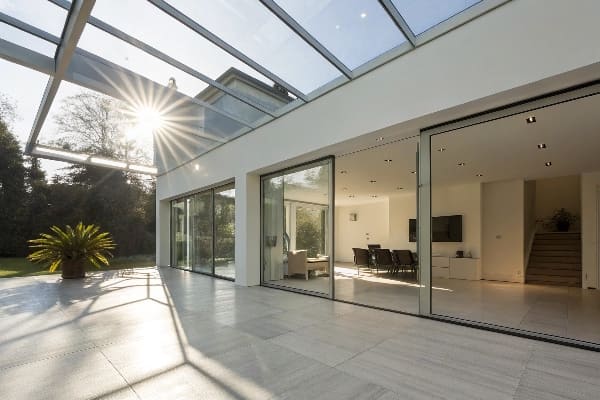 Minimalistische Glas Wintergarten mit Sonnenlicht durch die Decke und Schiebetüren
