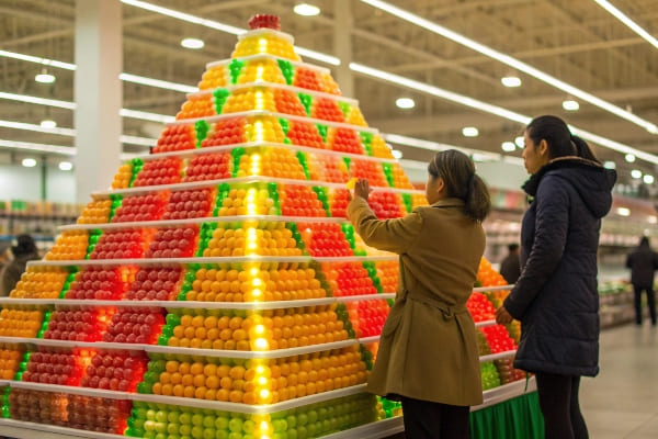 Présentation pyramidale vibrante de boules de fruits en plastique colorées à l'intérieur d'un supermarché