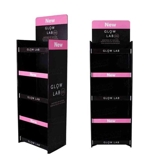 Glow Lab 美容产品纸板展架的侧面视图，突出了光滑的黑色饰面和粉色的“新品”标志。.