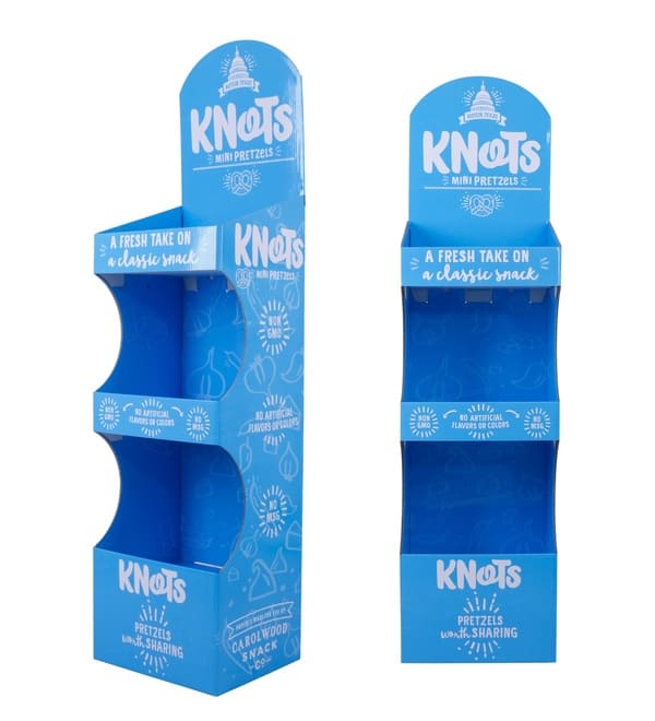 Вид сбоку и спереди на синюю напольную подставку из гофрированного картона, демонстрирующую трехполочное отделение для хранения пакетов с закусками.