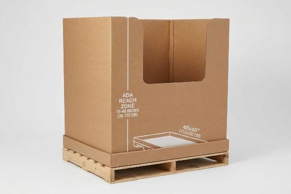 Brown corrugated cardboard POP display on a wooden pallet, showing ADA Reach Zone 15-48 Inches (38-122 Cm) and GMA 48x40 Inches (122x102 Cm) dimensions.