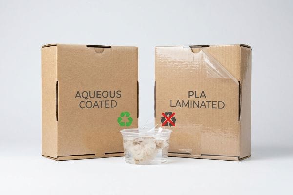 Aqueous Coated cardboard box with green recycling symbol next to Pla Laminated box with red no-recycle symbol, showing repulping difference.