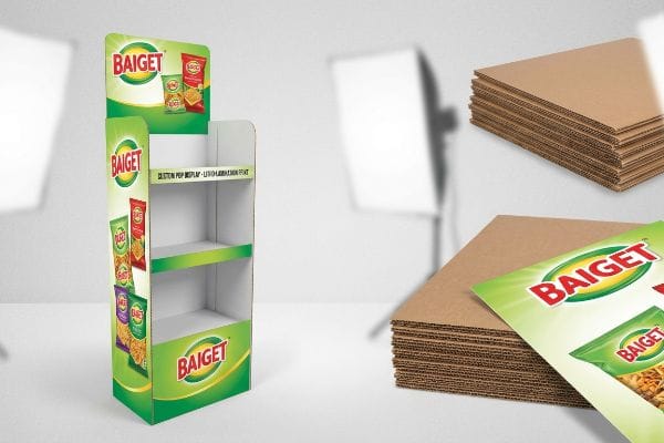 A custom Baiget Pop Display, featuring snack bags and Litho-Lamination Print, stands with raw corrugated cardboard sheets.