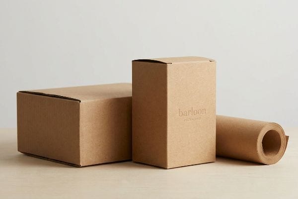 Three unbleached kraft paper packaging items: a horizontal box, a vertical Barloon Packaging box, and a roll of kraft paper.