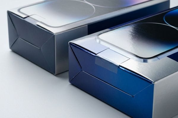 Duas caixas de embalagem para varejo em azul brilhante e prata com laminação refletora, exibindo um acabamento de película brilhante.