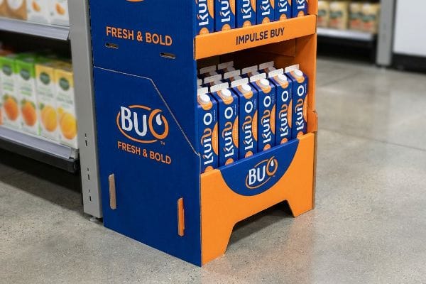 En el punto de venta se muestra un expositor POP de cartón azul y naranja para Buo Fresh & Bold, que exhibe varios envases de Kuroo y una sección de compra impulsiva.