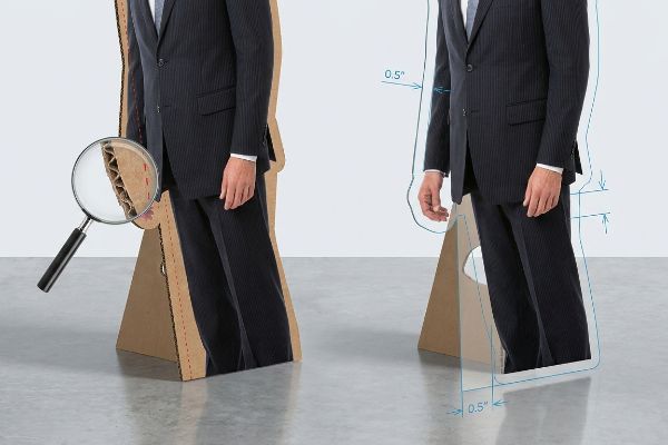 Detailansicht eines ausgeschnittenen Wellpappkartons mit Lupe, die die Schnittkante zeigt, daneben ein Diagramm, das einen 0,5-Zoll-Beschnittzugabe für präzises Konturschneiden veranschaulicht.