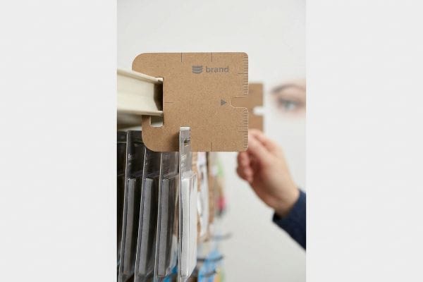 Cabeçalho de papelão marrom com clipes, logotipo da marca, marcações de régua integradas e entalhe para medição precisa a 50 polegadas (127 cm) na altura dos olhos, ideal para pontos de venda.