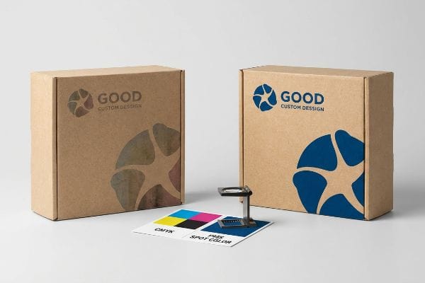 Kraft paper boxes with 'Good Custom Design' logos, contrasting faded CMYK and vibrant blue PMS Spot Color, with a CMYK/PMS swatch card and loupe.
