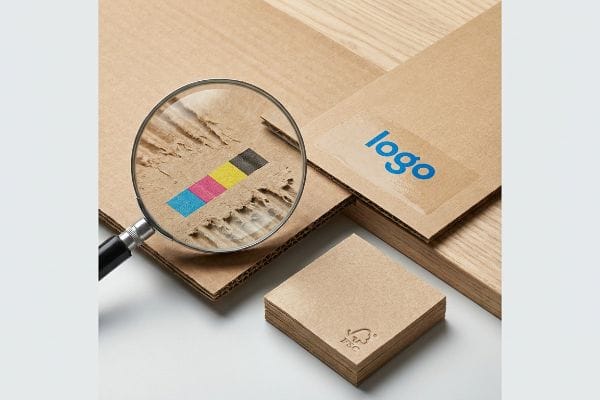 放大镜显示瓦楞纸板上的 CMYK 色条,纸板为 FSC 认证纸板,并印有蓝色“标志”。.