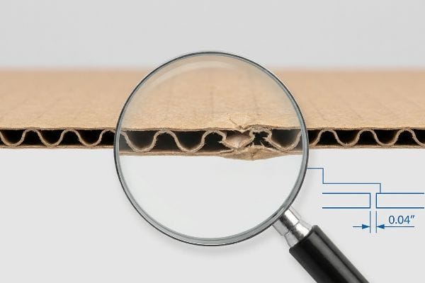 Corrugated cardboard cross-section with magnifying glass showing a damaged B-flute and a 0.04-inch humidity buffer clearance diagram.