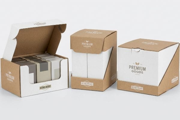 Three retail-ready display boxes, made of kraft and white corrugated board, showcase 'Premium Goods' branding and 'Retail-Ready' badges. One open box reveals inner products, while others are closed.