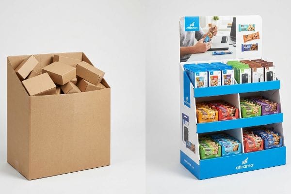 Brown corrugated cardboard dump bin filled with smaller boxes next to a blue and white Atirama multi-tiered retail display showcasing snack bars.