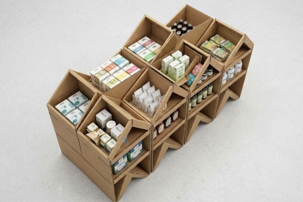 A modular corrugated cardboard retail display showcases various packaged products, emphasizing sustainable visual merchandising and spatial efficiency.