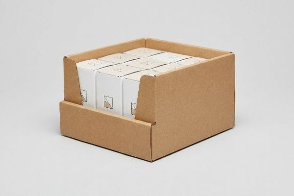 Brown corrugated cardboard PDQ display tray showcasing white product boxes with a subtle geometric design, optimized for quick merchandising.