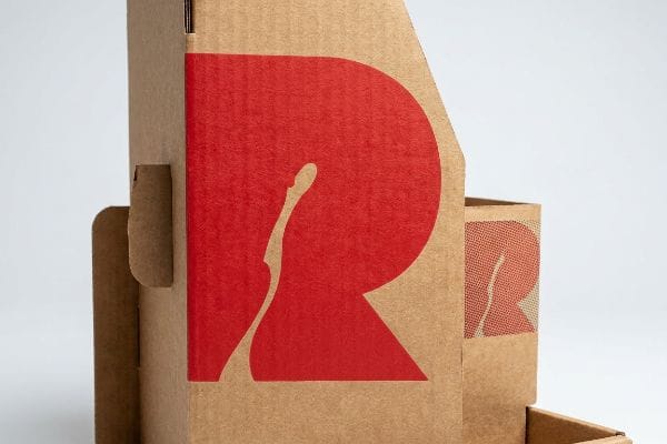 Brown corrugated cardboard POP display featuring a vibrant, solid red 'R' logo, highlighting spot color printing for brand continuity.