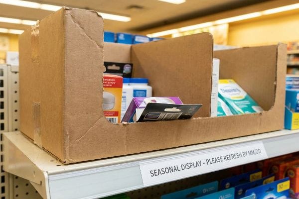 A brown corrugated cardboard seasonal display unit sits on a retail shelf, featuring a label that reads 