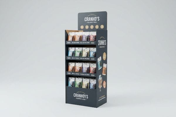 A tall, dark grey corrugated cardboard floor stand display for Cranho's Premium Treats, featuring four tiers of individually packaged pet treats for Medium Dogs.