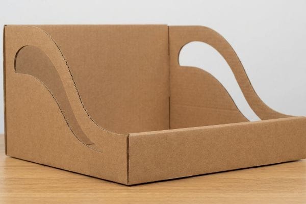 Brown corrugated cardboard display tray with curvy, die-cut side panels, showcasing structural contrast for visual disruption.