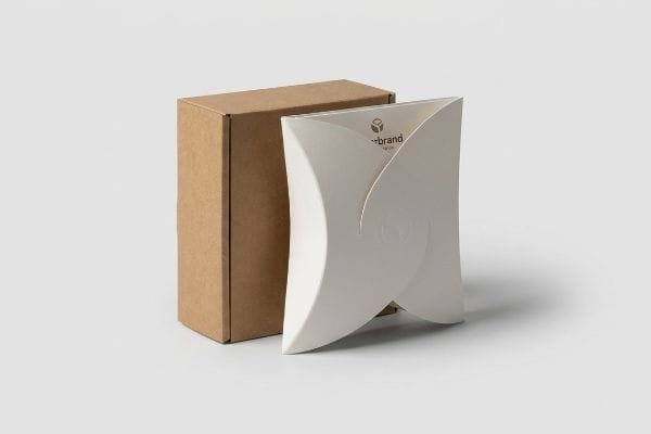 White die-cut paperboard package with sweeping curves and Yourbrand W100 logo, beside a plain brown rectangular cardboard box.