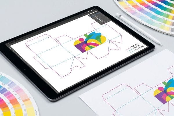 Tablet displaying a packaging dieline with magenta 'Cut Path' and cyan 'Fold Path' vector lines for automated die-cutting, next to color swatches.