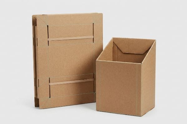 Brown corrugated cardboard pop-up stand, one flat-packed with visible crease lines, another partially assembled, showcasing auto-erecting design.