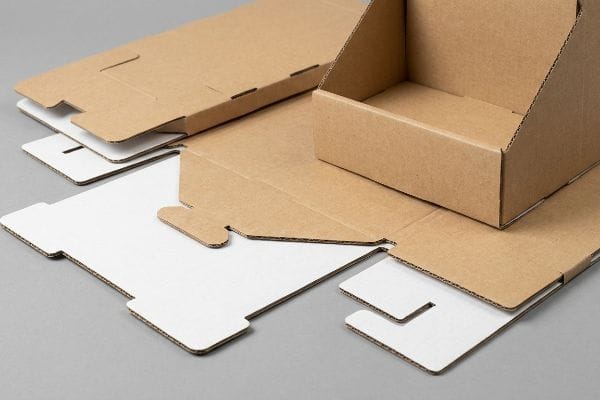 Corrugated cardboard display components, flat-packed and assembled, featuring natural brown and white surfaces, designed for pop-up retail.