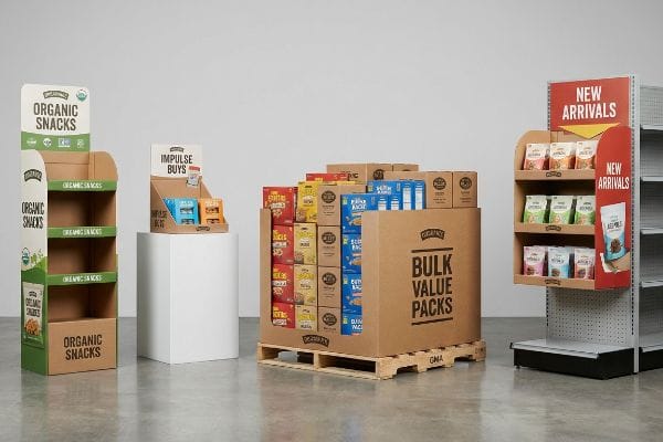 Corrugated cardboard retail displays: an Organic Snacks floor stand, Impulse Buys countertop unit, Bulk Value Packs pallet merchandiser on a GMA pallet, and New Arrivals sidekick power wing.