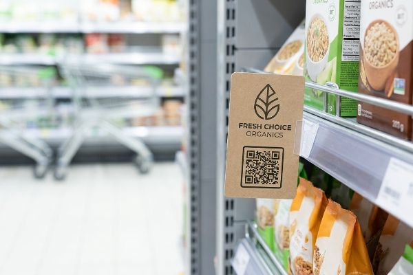Brown cardboard Fresh Choice Organics shelf talker with a QR code on a retail grocery aisle shelf.