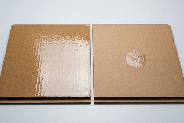 棕色瓦楞纸板,一张带有全UV光面涂层,另一张带有哑光涂层和局部UV立方体标志。.