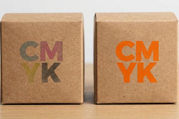 يعرض صندوقان من ورق الكرافت طباعة CMYK: ألوان معالجة باهتة على اليسار، ولون برتقالي نابض بالحياة على اليمين.