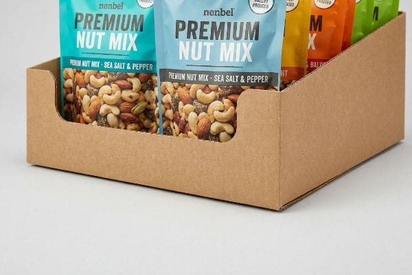 Corrugated cardboard display tray with low front lip, featuring Nenbel Premium Nut Mix - Sea Salt & Pepper pouches for optimal product visibility.