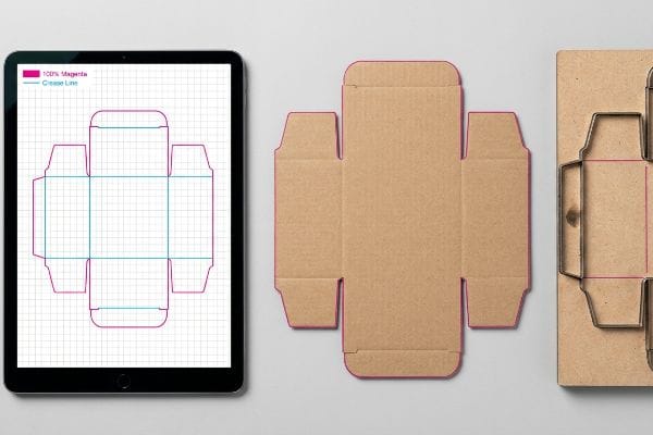 Digital dieline on a tablet shows 100% Magenta cut lines and Crease Lines, alongside a kraft cardboard die-cut and its steel rule die.