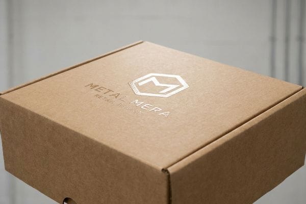 Custom retail packaging is showcased on a brown corrugated box with a metallic Metal Mera Retail Design logo.