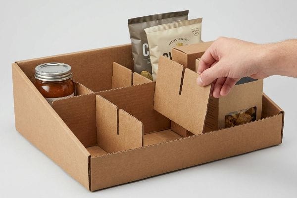 Kraft corrugated modular slotted dividers being assembled by hand into a retail tray for mixed SKU cross-merchandising.