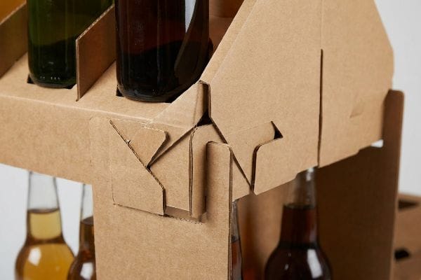 Precision-cut origami-style paper locks in a natural brown corrugated board beverage carrier, showcasing the mono-material interlocking tabs.