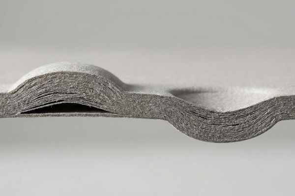 Examining the cross-section of a gray paperboard, multiple compressed fiber layers reveal the structural integrity of an embossed tactile finish.