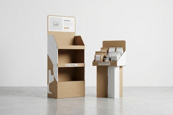 Two brown cardboard displays, a tall Pop Floor Display with empty shelves and a smaller Pop Counter Tray filled with product packages, both featuring white graphics.
