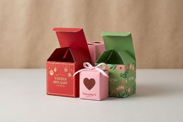 Seasonal gift boxes featuring red Winter Holiday, pink Valentine's with heart cutout, and green Spring floral designs.