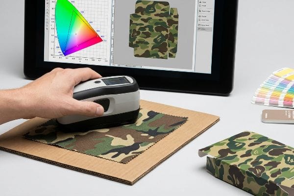 Utilizando un espectrofotómetro, se mide una muestra de tela de camuflaje para la igualación de colores CMYK en pantalla.