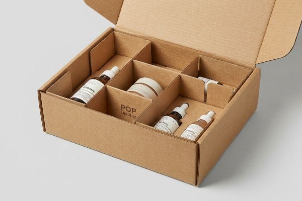 Kraft cardboard box with modular E-flute dividers holding The Ordinary cosmetic bottles and a jar, featuring a 