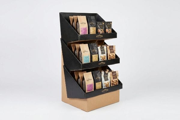 Three-tiered black and brown cardboard angled display stand, featuring coffee and snack bags with gold 'Coffee' branding, optimized for impulse sales.