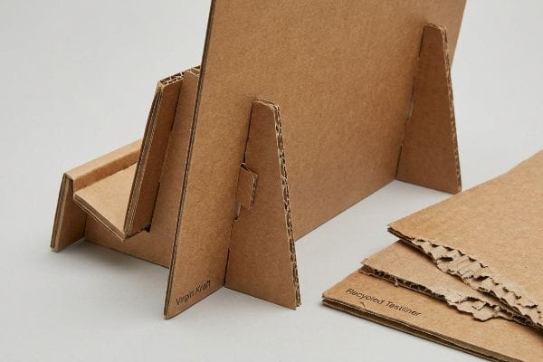 Virgin Kraft corrugated cardboard display stand with a separate Recycled Testliner piece, illustrating material differences for friction-fit assembly.