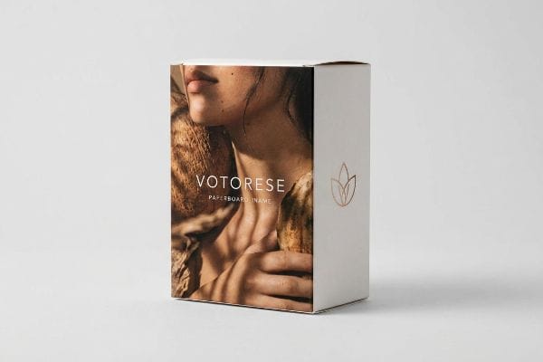 White paperboard box with a Votorese continuous-tone photographic print of natural skin tones and organic textures, accented by a gold foil logo.