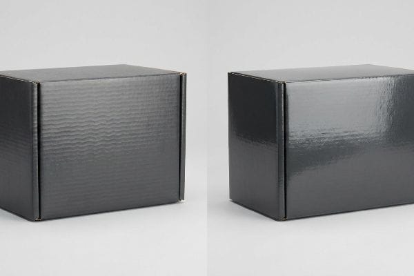 Dark grey corrugated boxes, one showing the washboard effect, the other a smooth, glossy, camera-ready finish for premium PR.