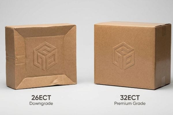 Two brown corrugated boxes: a 26ECT Downgrade box with visible crushing and a crisp 32ECT Premium Grade box, both featuring an embossed logo.